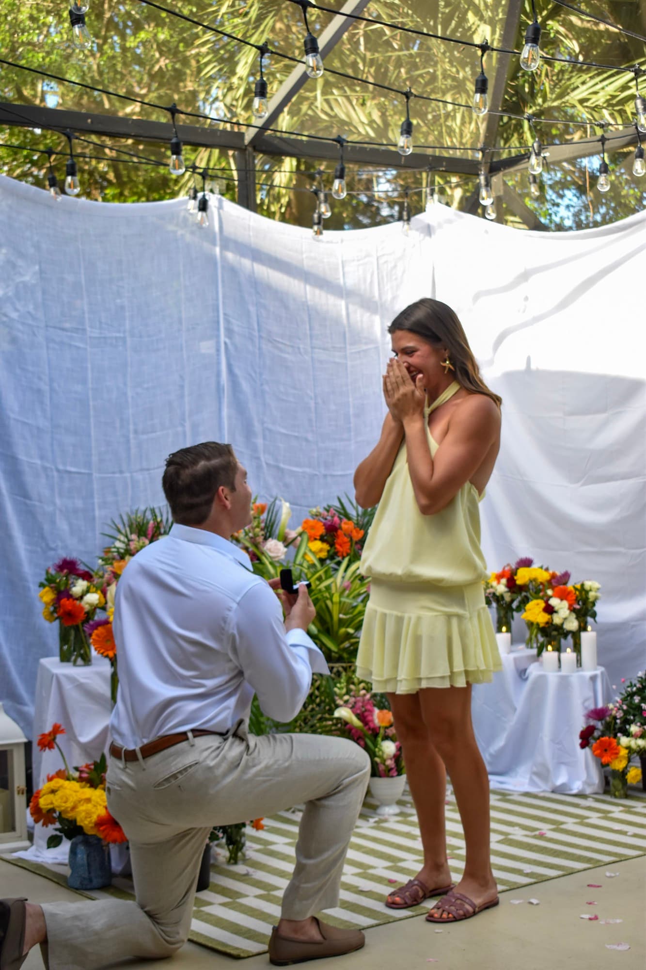 Jon down on one knee holding the ring box, Morgan's hands pressed to her mouth.